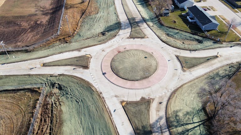 High angle aerial shot of a roundabout surrounded by streets and green areas in Camanche, Iowa.