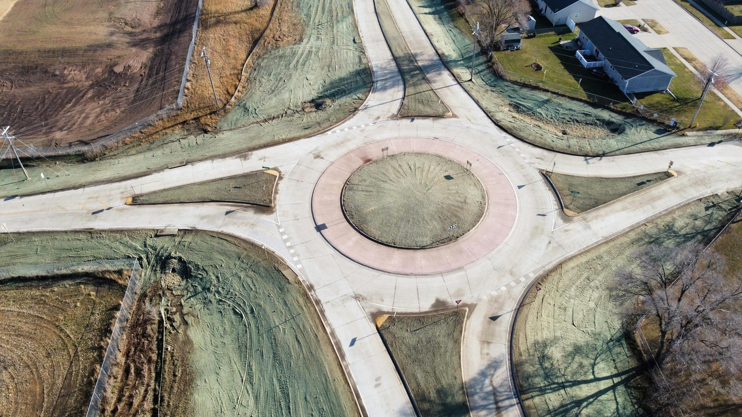 High angle aerial shot of a roundabout surrounded by streets and green areas in Camanche, Iowa.